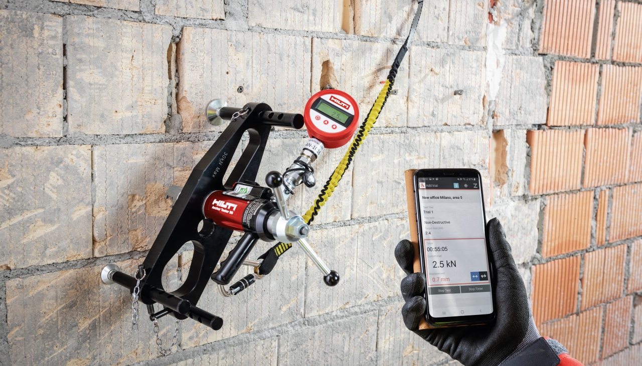 Hilti töötaja kasutab Hilti tööriista telefoni hoidmiseks